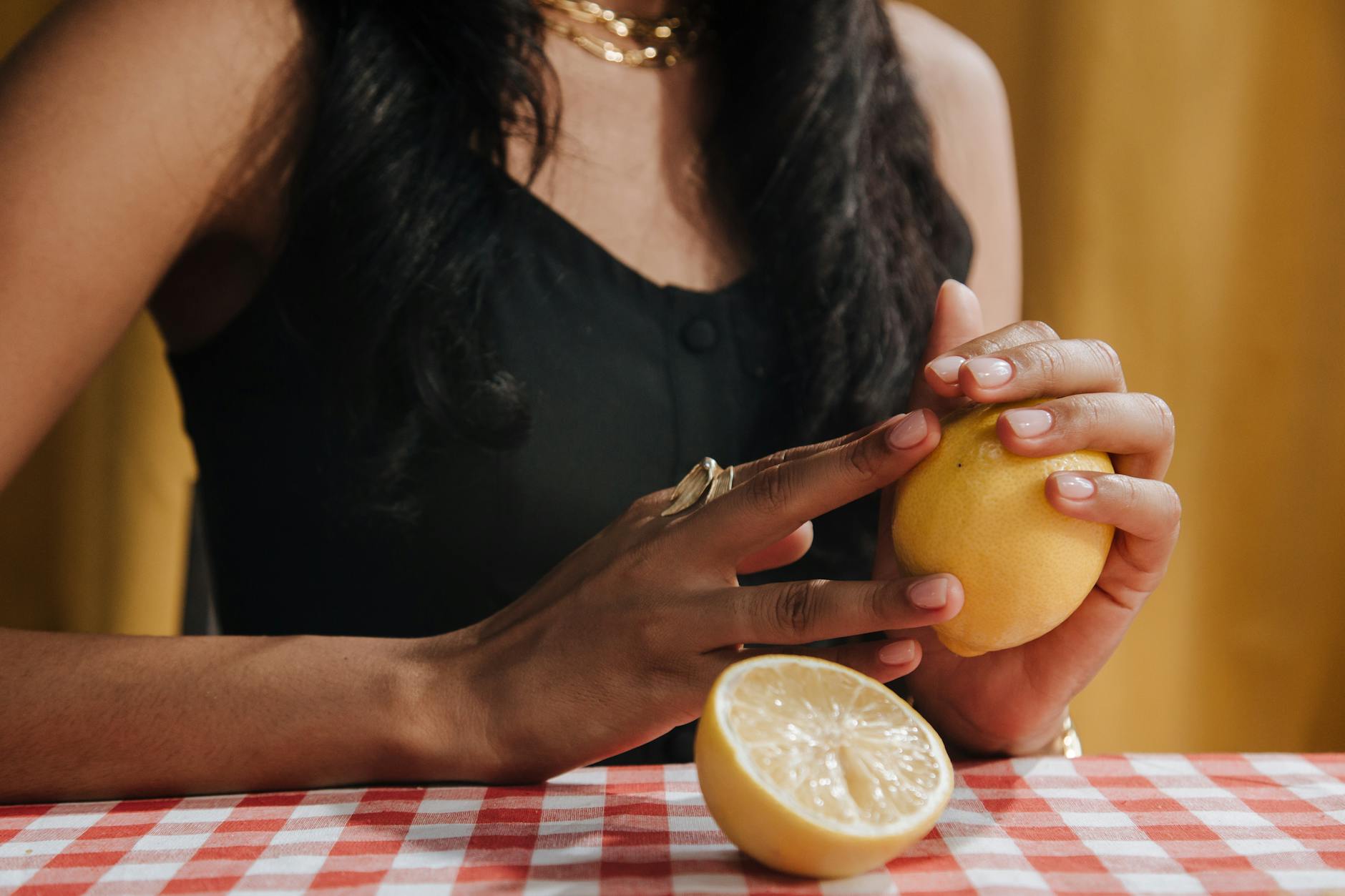A hand holding a fresh lemon on a soft pink background, symbolizing gentle healing and natural recovery