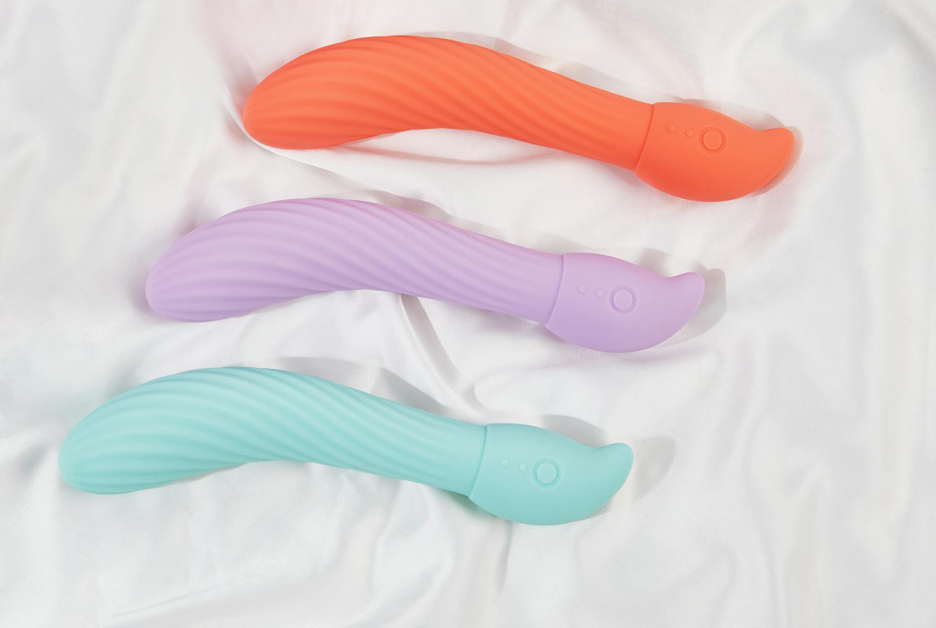 A teal lemon clitoral vibrator resting on smooth white silk fabric, showcasing the minimalist design of air-suction technology
