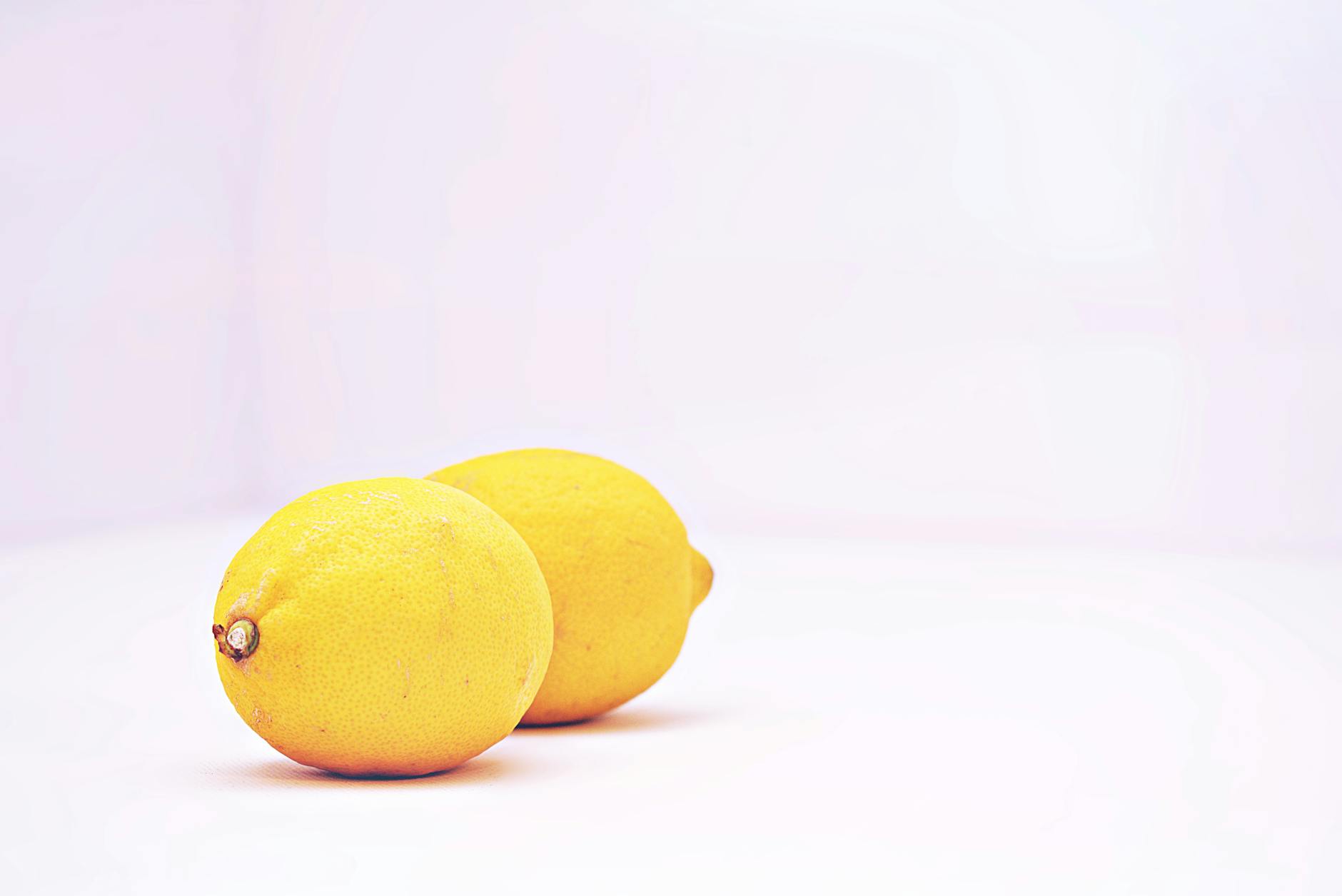 Two hands holding silicone vibrators against a pastel background