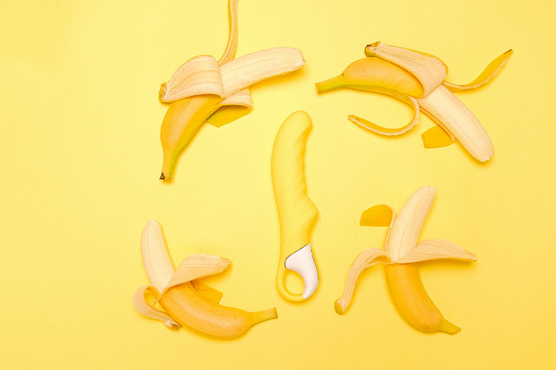 Yellow lemon vibrator surrounded by fresh lemons and fruit on a bright yellow background