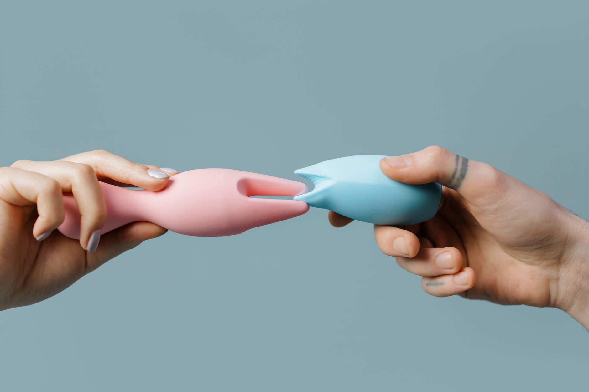 Blue silicone lemon vibrator held in hand against purple background
