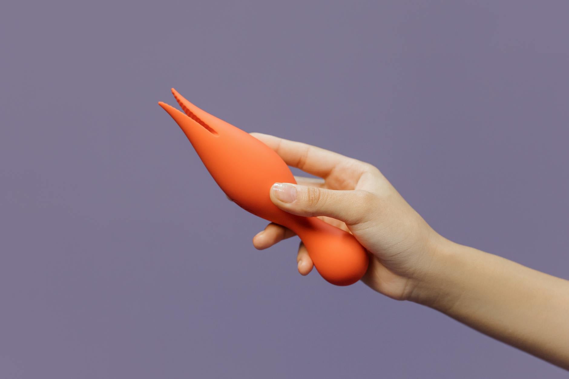 A hand holding a lemon vibrator against a minimalistic backdrop, symbolizing focused sensuality and grounded pleasure.
