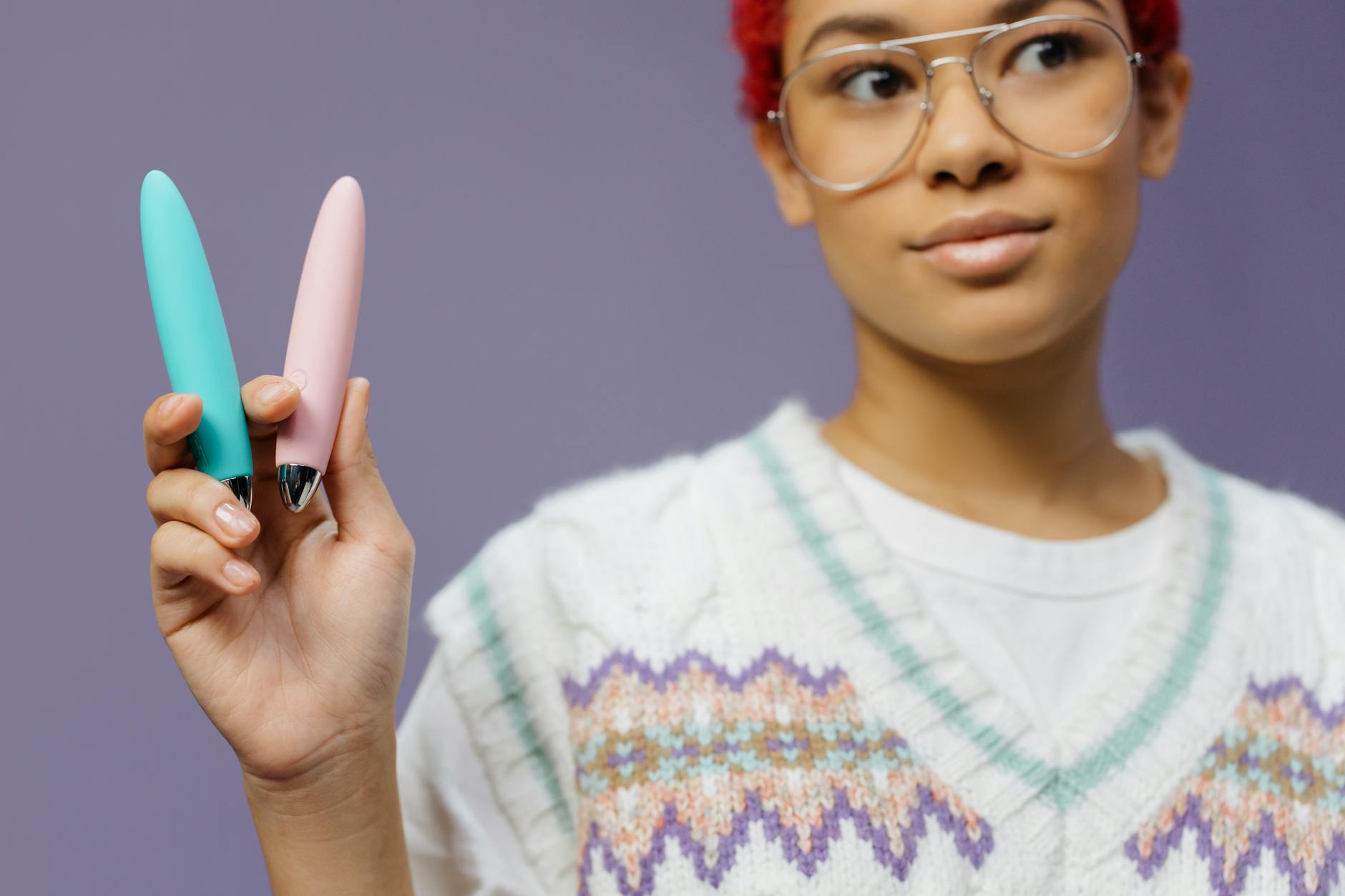 Woman holding colorful vibrators, exploring extended pleasure techniques