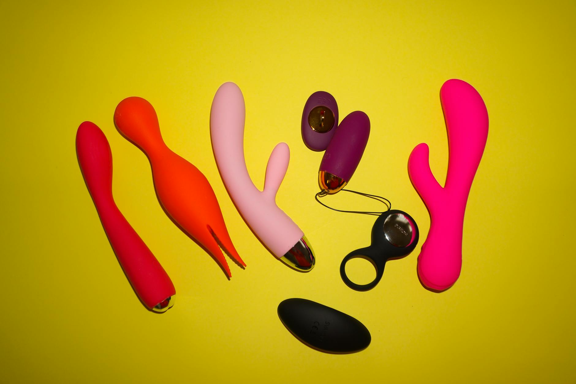Yellow silicone vibrator surrounded by fresh lemons on a bright yellow background